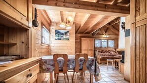 L’intérieur d’un chalet en bois comprend une table à manger, des chaises, un canapé et un coin cuisine.