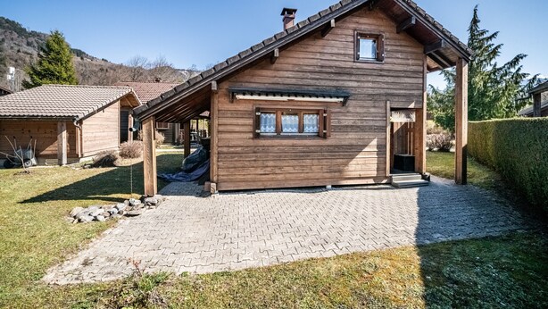 Une cabane en bois avec un toit en tuiles, une véranda et une allée pavée.