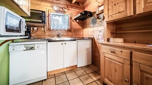 Une cuisine aménagée dans une cabane en bois, équipée d’un four à micro-ondes, d’un grille-pain et d’un lave-vaisselle.