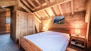 Une chambre dans une cabane en bois, avec un lit, des tables de chevet, une lampe et un tableau au mur.