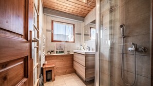 Un bagno compatto con doccia, una piccola finestra e pareti in legno.