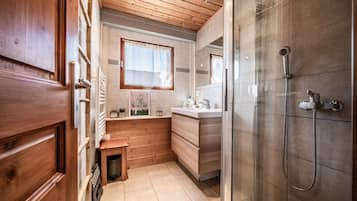 A compact bathroom with a shower, a small window, and wooden walls.