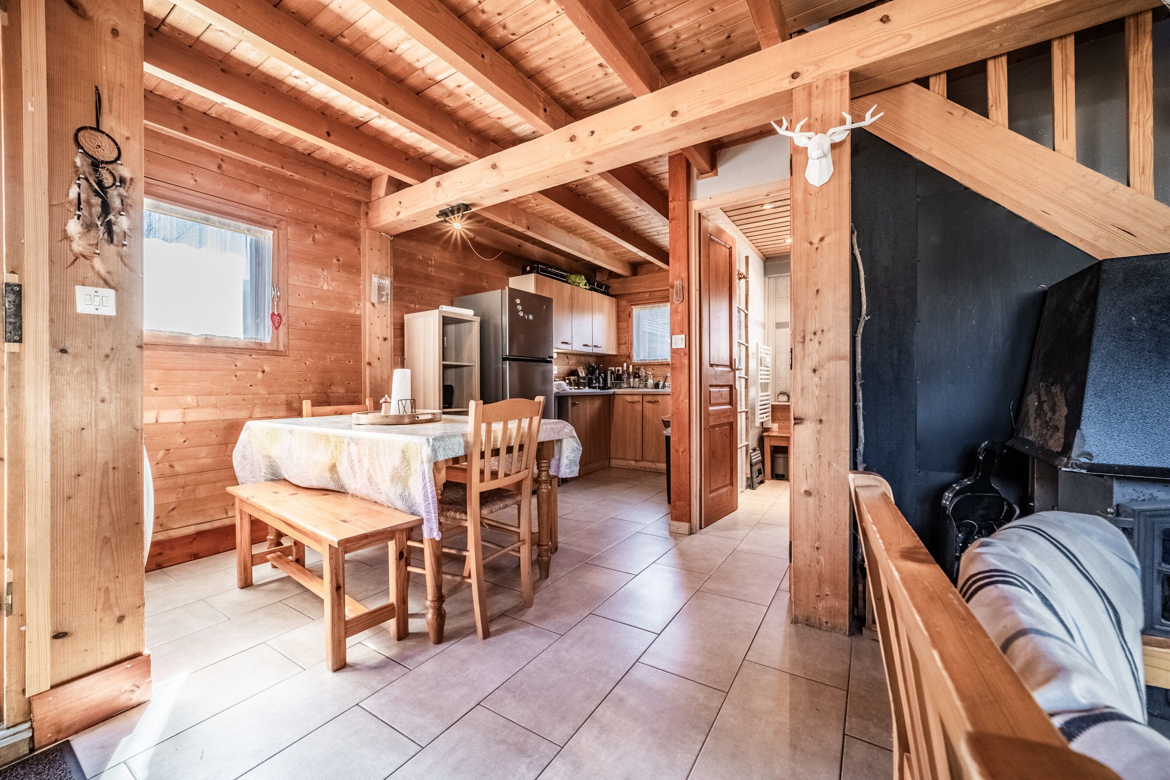 Interior de una cabaña de madera con comedor, cocina y chimenea.