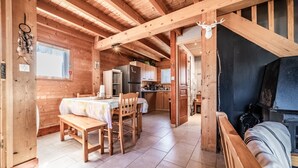 Interno di una baita in legno con zona pranzo, cucina e camino.