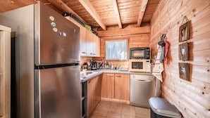 Una cucina compatta con frigorifero in acciaio inossidabile, pensili e basi in legno, un forno a microonde ed una lavastoviglie.