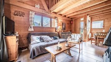 L’intérieur d’un chalet confortable, avec un lit, des meubles en bois, un téléviseur et une cheminée.