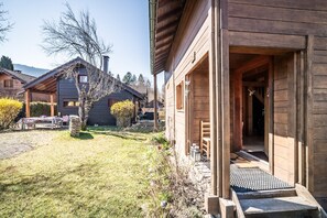 A wooden cabin with a covered porch, a small outdoor seating area, and a clear view of the surrounding landscape. - Chalet “6p Classique - Le Rhodo” with Mountain View, Private Terrace, and Wi-Fi (Verchaix)