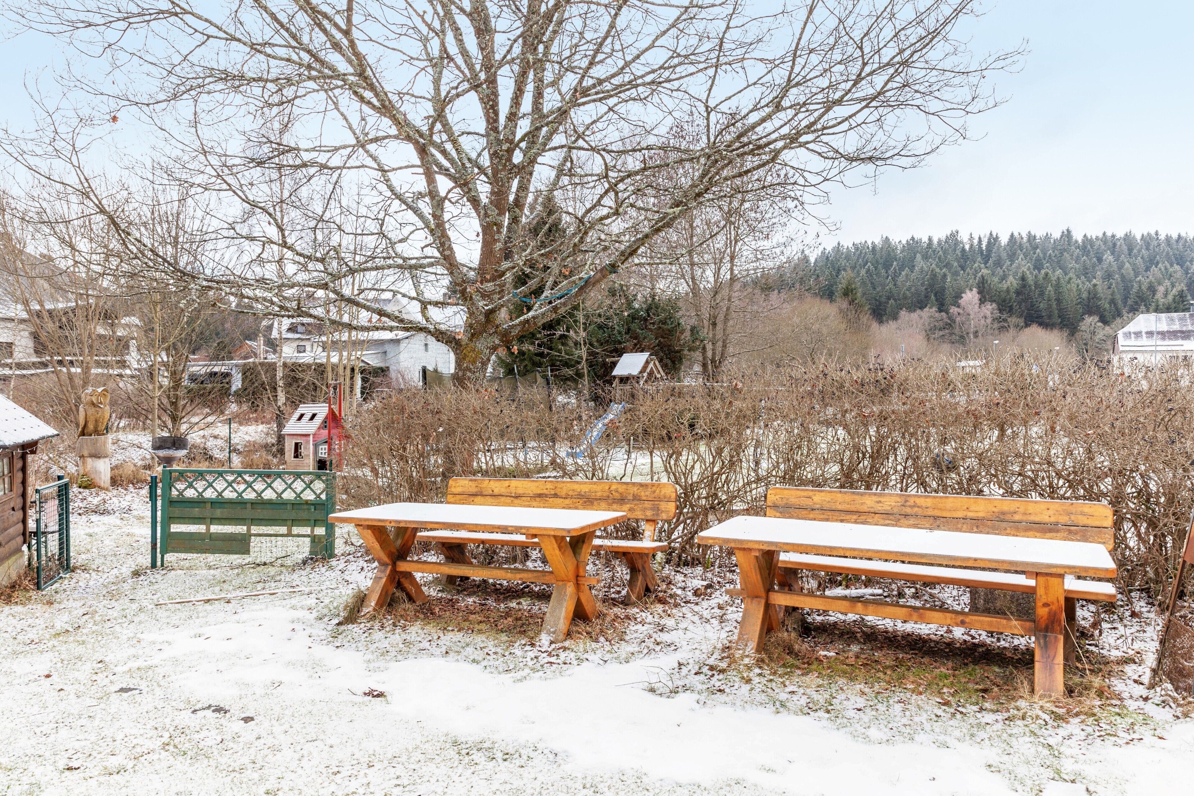 A snowy outdoor area with wooden benches and a gate.