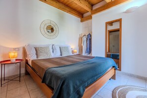 Ein Schlafzimmer mit einem hölzernen Bett, einer runden Wanddekoration, einem Nachttisch mit Lampe und einem Kleiderständer.