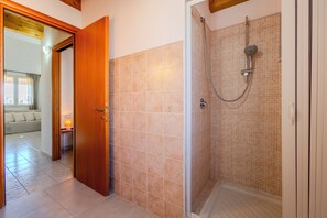 Ein Badezimmer mit Dusche, Fliesenwänden und einer Holztür.