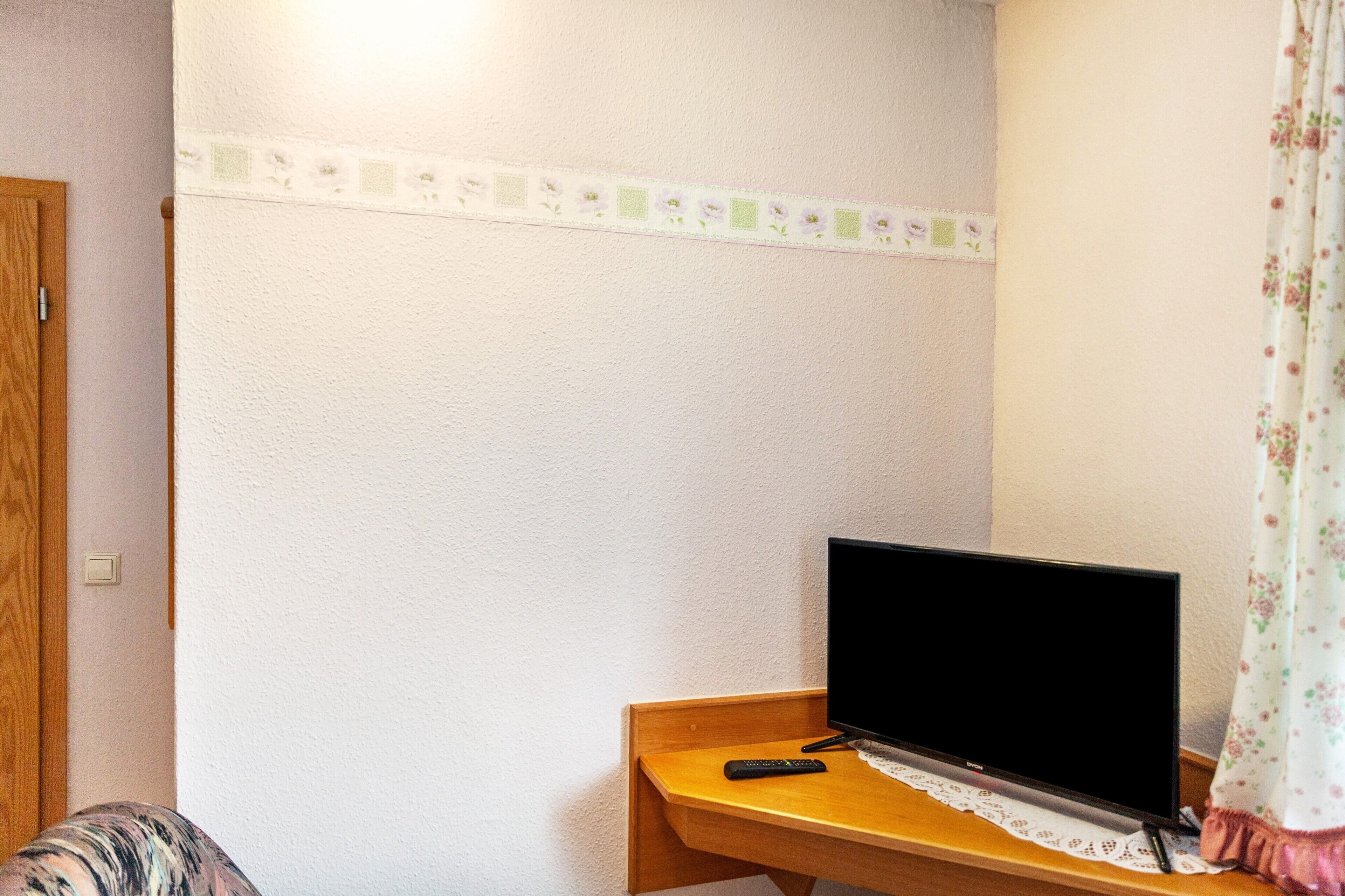 Une pièce comprenant un bureau en bois, un téléviseur et une télécommande.