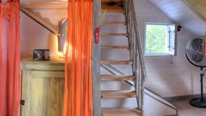 A wooden staircase leading to a loft area with a window, a fan, and a rustic wooden cabinet. - Le Balcon De Loire - Curry Room: Escape and Serenity by the Loire (La Chapelle sur Loire)