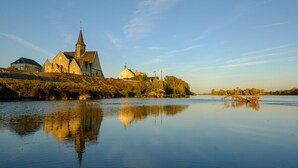 A calm river with a church and residential buildings on the opposite bank. - Le Balcon De Loire - Curry Room: Escape and Serenity by the Loire (La Chapelle sur Loire)