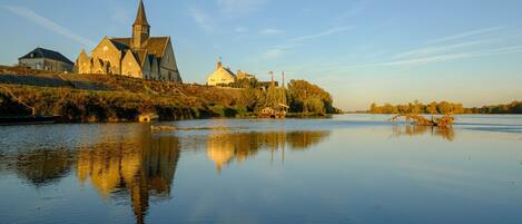 En stilla flod med en kyrka och bostadshus på den motsatta stranden.