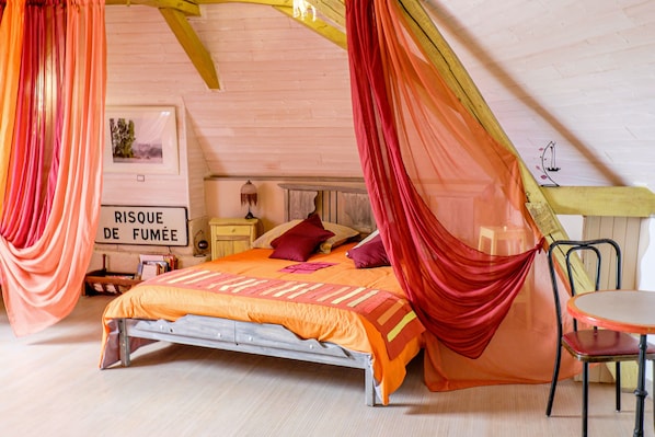 Ein Schlafzimmer mit Bett, Nachttisch, Sessel und Tisch.
