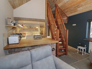 A kitchen with a wooden counter, a built-in oven, and a brick wall. There is a wooden staircase leading to an upper level. - The Barn on The Lagoon (Droitwich)