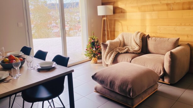 Ett modernt vardagsrum med en väggpanel av trä, en soffa, ett soffbord och ett matbord med plats för fyra personer.
