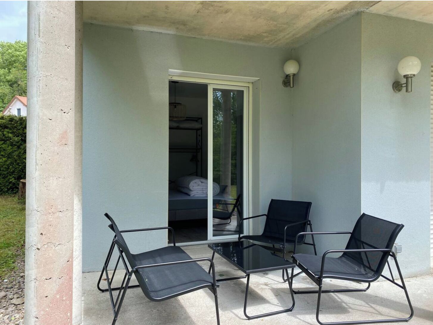 A balcony with two black metal chairs and a glass table.