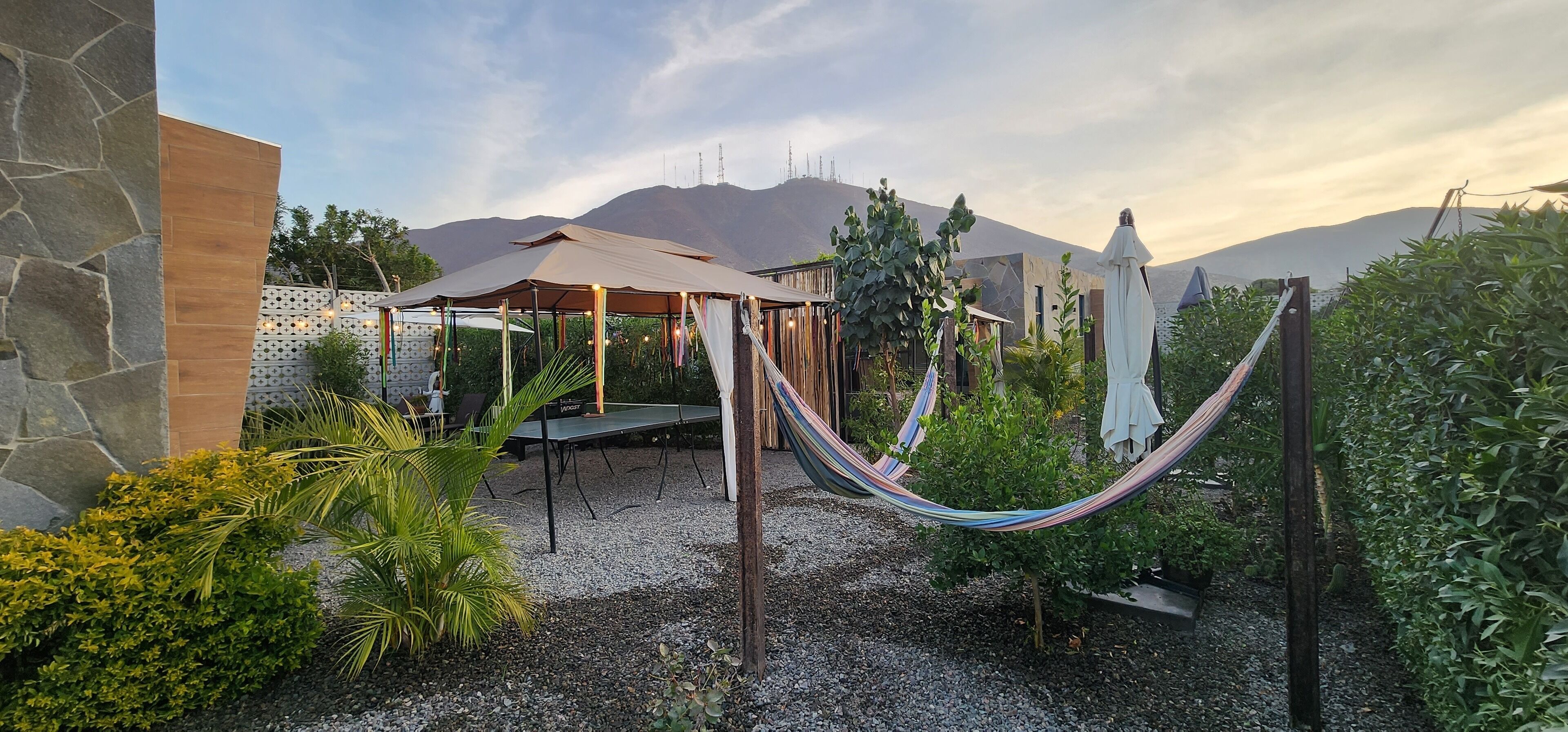Een terras met een hangmat, een tafeltennistafel en een overdekte zithoek.