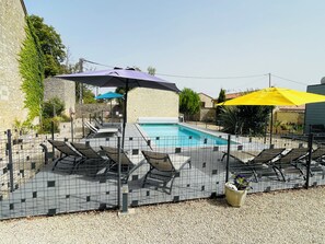 Ein Poolbereich mit Fliesenboden, Liegestühlen und Sonnenschirmen.