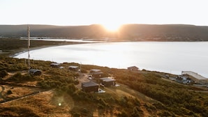 A coastal village with several small houses, a lighthouse, and a large body of water. - Lapointe Chalets - Chalet Deveau (Inverness County)