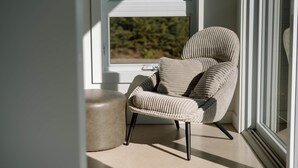 Una silla de diseño acanalado junto a una ventana con vista a la vegetación.