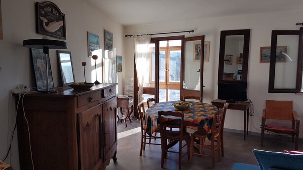 A dining area with a wooden table, chairs, a cabinet, and a television.