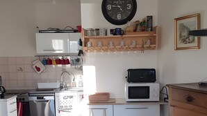 A kitchen with white cabinets, a microwave, a sink, and a clock on the wall.