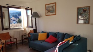 A living room with a sofa, a chair, a lamp, and two framed pictures on the wall.