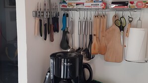 A kitchen with a coffee maker, utensils, and a cabinet.