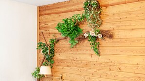 Un mur en bois agrémenté d’une composition végétale suspendue et d’une lampe fixée au mur.