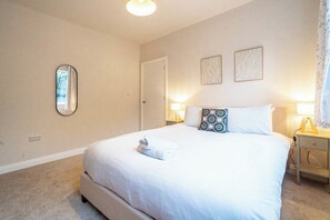 Una habitación de hotel con una cama grande, lámparas de noche, un espejo y dos obras de arte en la pared.