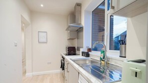 Una cocina moderna con lavavajillas integrado, un lavamanos de acero inoxidable y una ventana con vistas a una fachada de ladrillo.