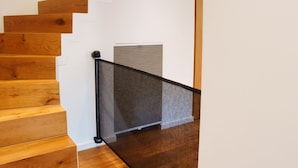 Eine Holztreppe mit schwarzer Geländer, weißen Wänden und einer Deckenleuchte.