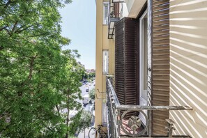 A view from a balcony overlooking a street with trees and buildings. - Glorieta (Madrid)