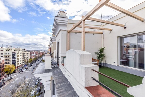 Un bâtiment moderne doté d’une terrasse sur le toit, agrémentée d’une pelouse artificielle et d’une pergola en bois.