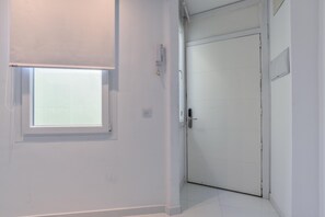 Une pièce blanche avec une fenêtre, une porte et un interrupteur sur le mur.