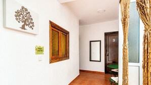 Ein Flur mit einer Holztür, die mit der Nummer 3 gekennzeichnet ist, einem gerahmten Spiegel und einem an der Wand befestigten Lichtschalter.