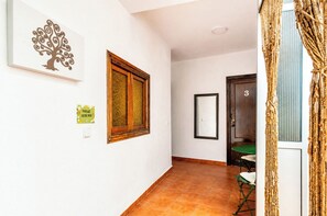 Ein Flur mit einer Holztür, die mit der Nummer 3 gekennzeichnet ist, einem gerahmten Spiegel und einem an der Wand befestigten Lichtschalter.