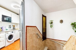 Eine kompakte Küche mit Mikrowelle, Waschmaschine und kleinem Spülbecken.