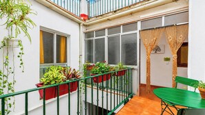Ein kleiner Balkon mit Blumentöpfen, einem grünen Tisch und einem Stuhl.