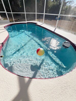 Piscina com borda azulejada, água cristalina e uma boia de praia.