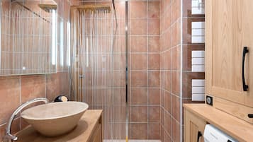A modern bathroom with a large sink, a shower with vertical glass panels, and wooden cabinetry.