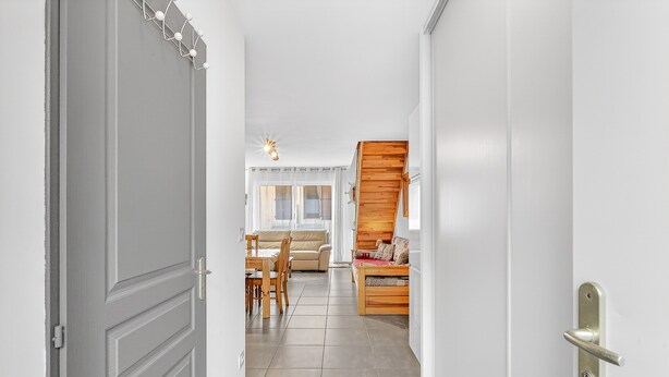 A hallway leading to a living area with a sofa, a dining table, and chairs.