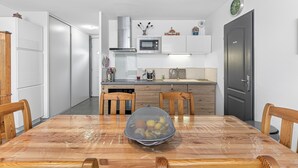 A modern kitchen with a microwave, stove, and wooden chairs around a table.