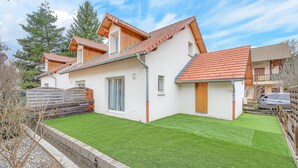 A modern house with a sloped roof, a well-maintained lawn, and a wooden deck.