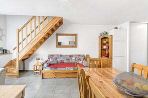 Una habitación con una escalera de madera, un sofá, una mesa de comedor y un armario.