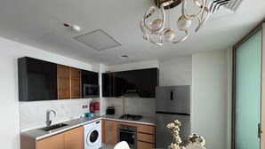 Eine moderne Küche mit Geschirrspüler, Herd und Kühlschrank. Es gibt einen Essbereich mit einem Glastisch und Stühlen.