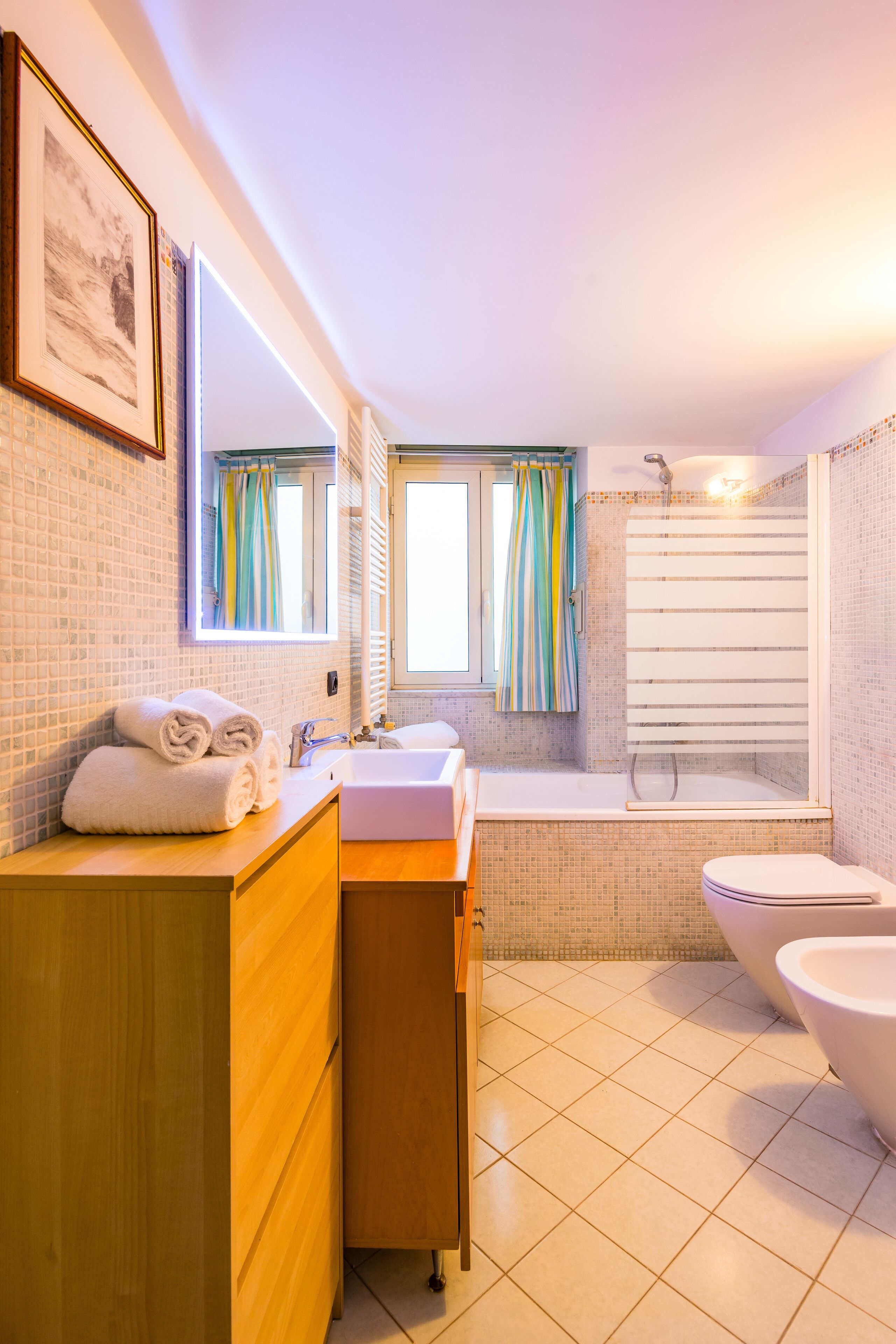 A bathroom with a wooden vanity, a sink, a toilet, and a bathtub.