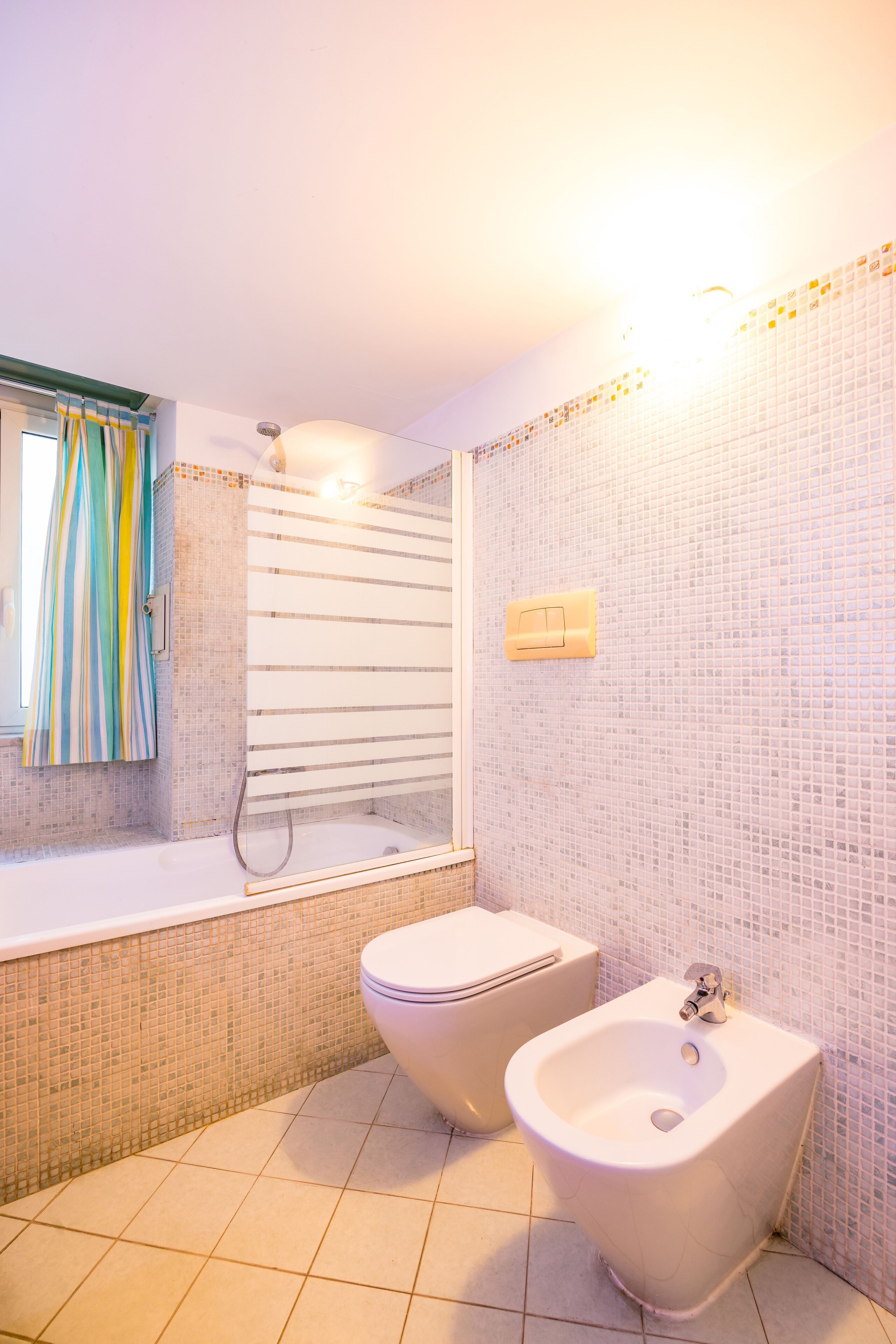 Een badkamer met een bad, een toilet en een hygiëneschuimer.